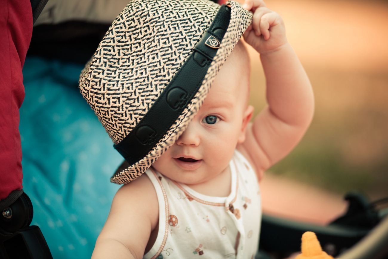 Baby S White Sleeveless Top Playing With Hat