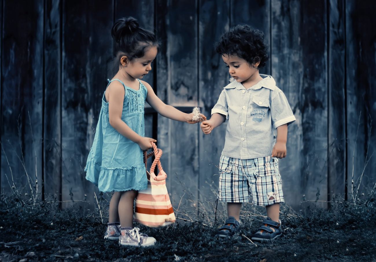 Boy and Girl Standing Near Wooden Wall